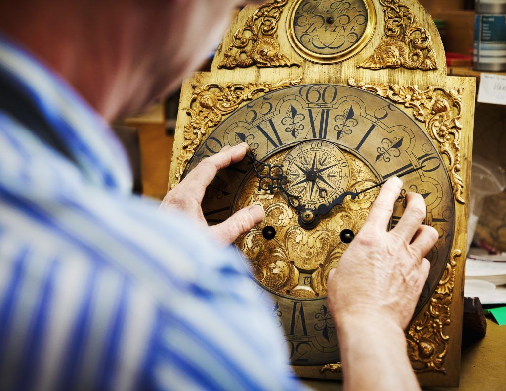 clock maker lifting clock off shelf
